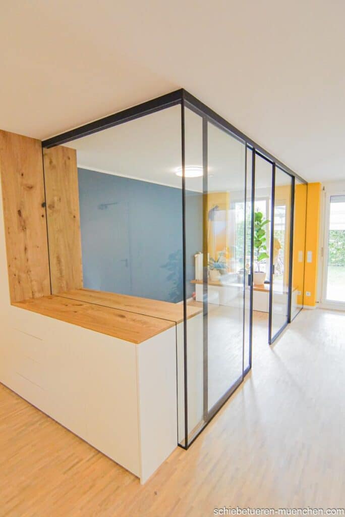 Schallisoliertes Home-Office im Wohnzimmer: Einbauschrank mit Festverglasung und schwarzem Rahmen, ergänzt durch schallgedämmte Schiebetüren mit Glasfüllung.
