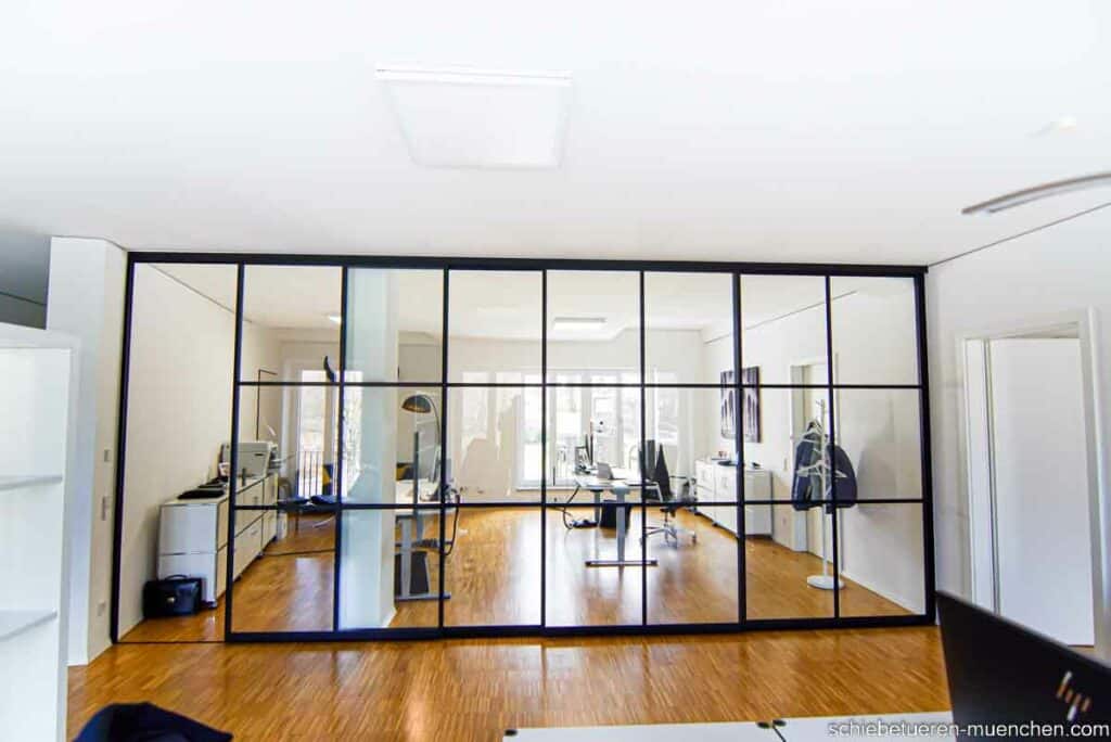 Ein Großes Büro wird bei Bedarf von Schwarzen Schiebetüren mit Glass Füllung und Sprossen im Loft style Schallhemmend in zwei Bereiche unterteilt. Maßanfertigung von Door360 München