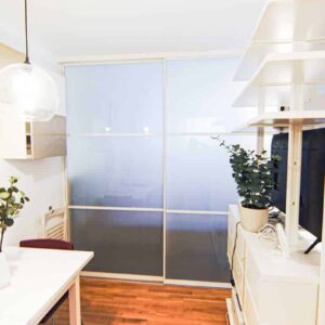 Abtrennung von Wohn- und Schlafbereich in einem Studio. Die Trenn Wand besteht aus zwei Schiebetüren mit Milchglas weißem Rahmen und Sprossen. Maßgefertigter Raumteiler von Door360 München