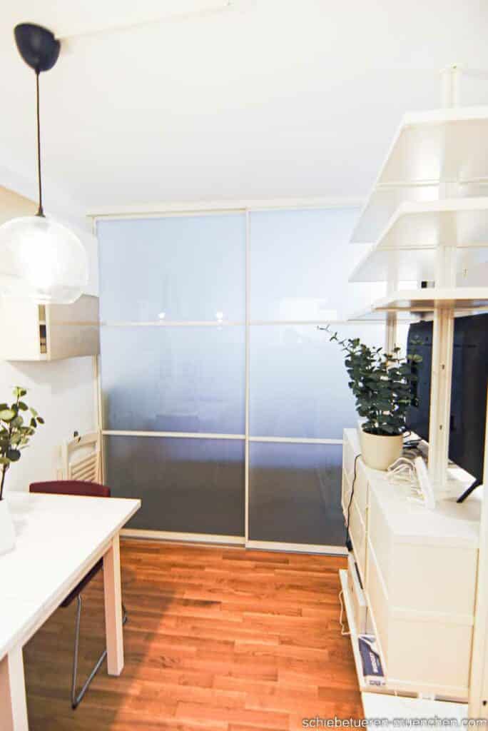 Abtrennung von Wohn- und Schlafbereich in einem Studio. Die Trenn Wand besteht aus zwei Schiebetüren mit Milchglas weißem Rahmen und Sprossen. Maßgefertigter Raumteiler von Door360 München