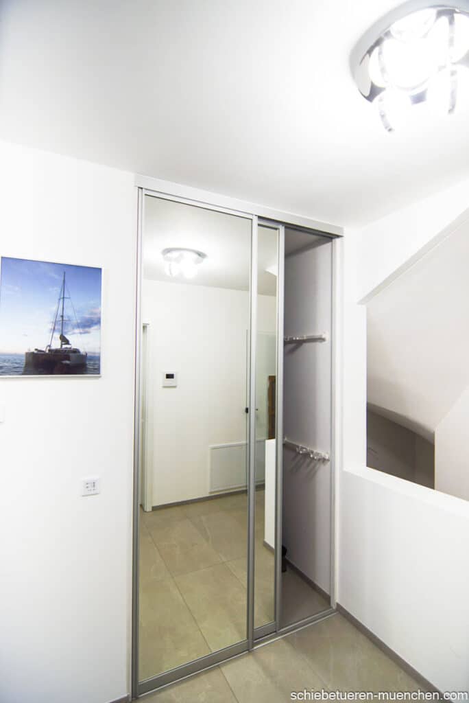 Flur Nische in der sich die Garderobe befindet kann mit Hilfe von Zwei Schiebetüren mit Spiegel Glasfüllung versteckt werden. Von Door360 München