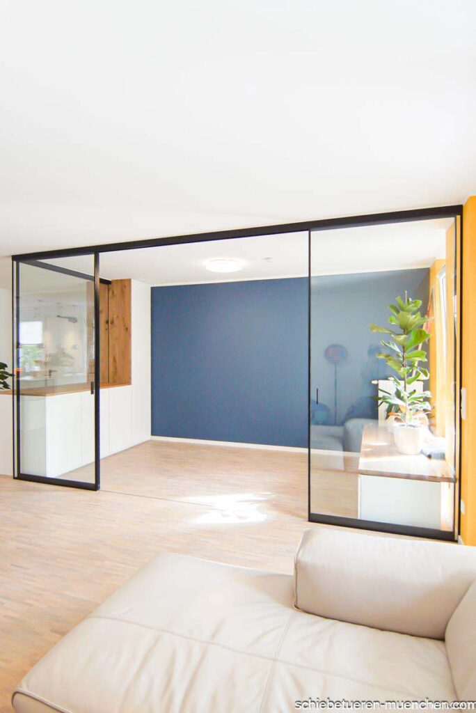 In einem Wohnzimmer wurde ein weiterer Raum als Home-Office mittels Einbauschrank Festverglasung und Schiebetüren mit Glasfüllung geschaffen. deer Rahmen ist Schwarz