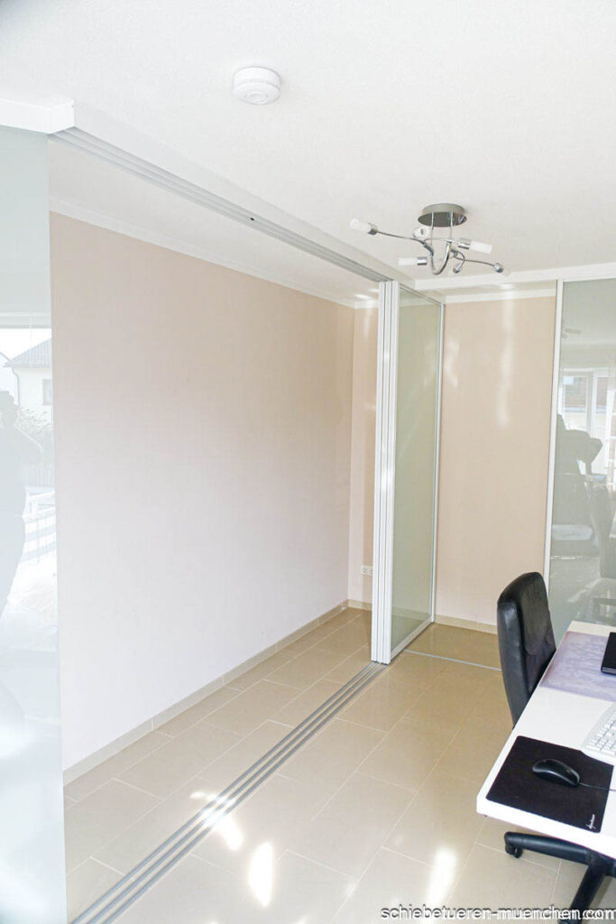 Flexibles Home Office mit Schrankfront als Trennwand, weißem Rahmen, mattem Glas und Door360 Schiebetüren in München.