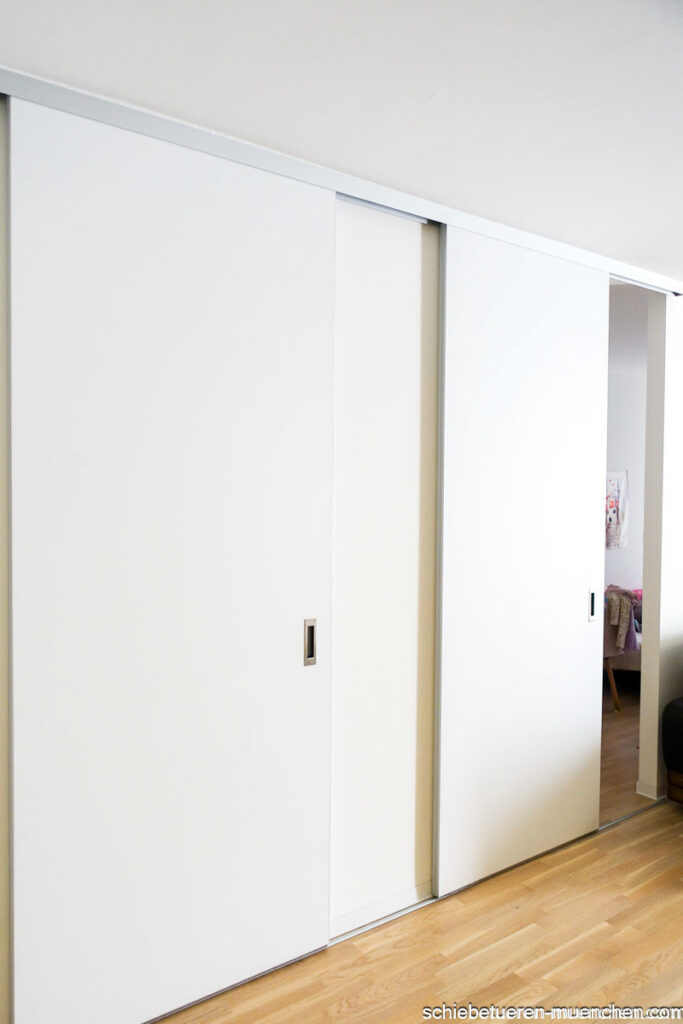 Zwei Raumteiler mit matt weißen holz Schiebetüren um das Home office vom Wohnbereich abzutrennen