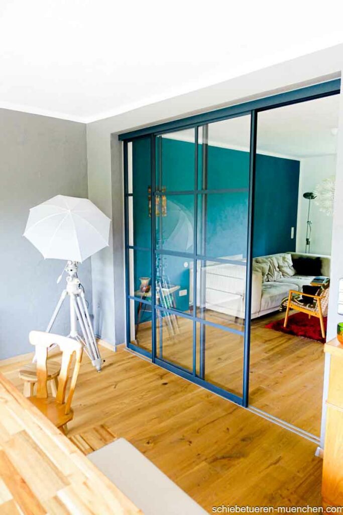 Anthrazitfarbene Schiebetüren im Industriedesign trennen Esszimmer und Wohnzimmer als Raumteiler. Maßgefertigt von Door360 Schiebetüren München.