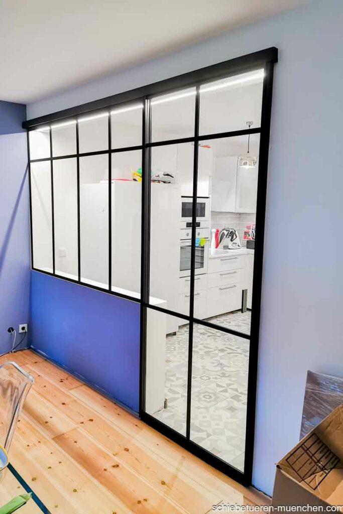 Eine Abtrennung zwischen Küche und Wohnbereich mit Festverglasung und Schiebetüren im Loft Syle in München
