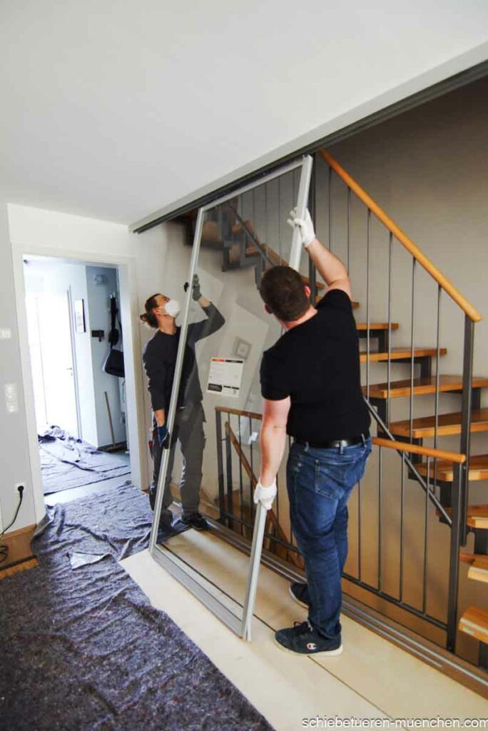 Mitarbeiter von Door360 beim fachgerechten Einhängen einer Schiebetür zur Gestaltung des Treppenhauses.