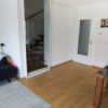 Einflügelige Loft-Schiebetür aus Klarglas mit weißem Rahmen, als elegante Treppenhaus-Abtrennung montiert.
