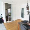 Einflügelige Loft-Schiebetür aus Klarglas mit weißem Rahmen, als elegante Treppenhaus-Abtrennung montiert.