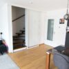 Einflügelige Loft-Schiebetür aus Klarglas mit weißem Rahmen, als elegante Treppenhaus-Abtrennung montiert.