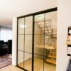 Zweiteilige Loft-Schiebetür mit schwarzem Aluminiumrahmen und Glaseinsätzen im Industrie-Look, als Abtrennung zwischen Treppenhaus und Wohnbereich.