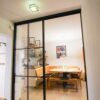 Loft-Schiebetür mit schwarzem Aluminiumrahmen und Sprossen im Industrie-Look, als Raumabtrennung zwischen Flur und Essbereich.