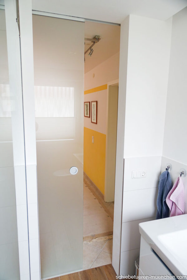 Badezimmer-Schiebetür aus klarem Glas, geöffnet, Blick in den angrenzenden Flur