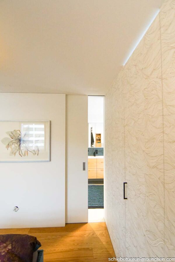 Badezimmer-Schiebetür aus Holz, flächenbündig in die Wand laufend – elegante Verbindung zwischen Schlafzimmer und Bad, München