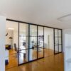 Moderner Büro-Raumteiler von door360, Schiebetüranlage mit schwarzen Sprossen und klaren Glasfeldern.