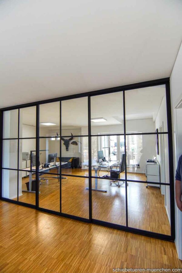 Industriedesign Raumteiler im Büro – deckenmontierte Schiebetüren von door360 mit schwarzen Sprossen.