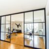 Industriedesign Raumteiler im Büro – deckenmontierte Schiebetüren von door360 mit schwarzen Sprossen.