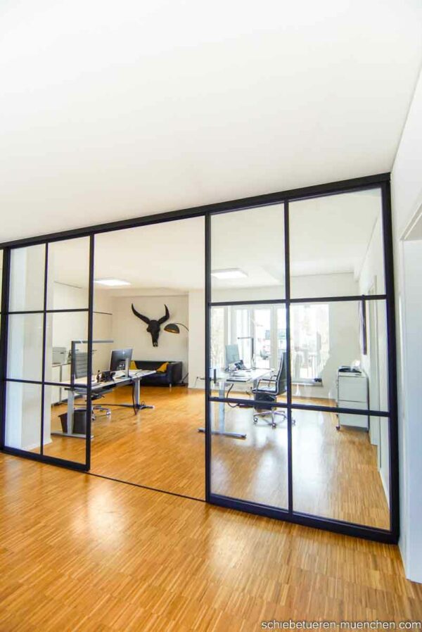 Industriedesign Raumteiler im Büro – deckenmontierte Schiebetüren von door360 mit schwarzen Sprossen.