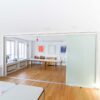 Moderner Konferenzraum mit geöffnetem Schiebetür-Raumteiler aus Glas für flexible Raumtrennung