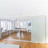 Raumteiler im Konferenzraum mit Schiebetüren aus Glas, teilweise geschlossen für klare Struktur.