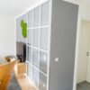 Raumteiler aus Klarglas mit weißen Sprossen, Profilfarbe Weiß, als Verbindung zwischen Flur und Wohnzimmer – door360 Schiebetüren München.