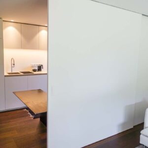 Breiter Raumteiler mit weißer Schiebetür – Küchenbereich flexibel abtrennbar, deckenintegrierte Laufschiene