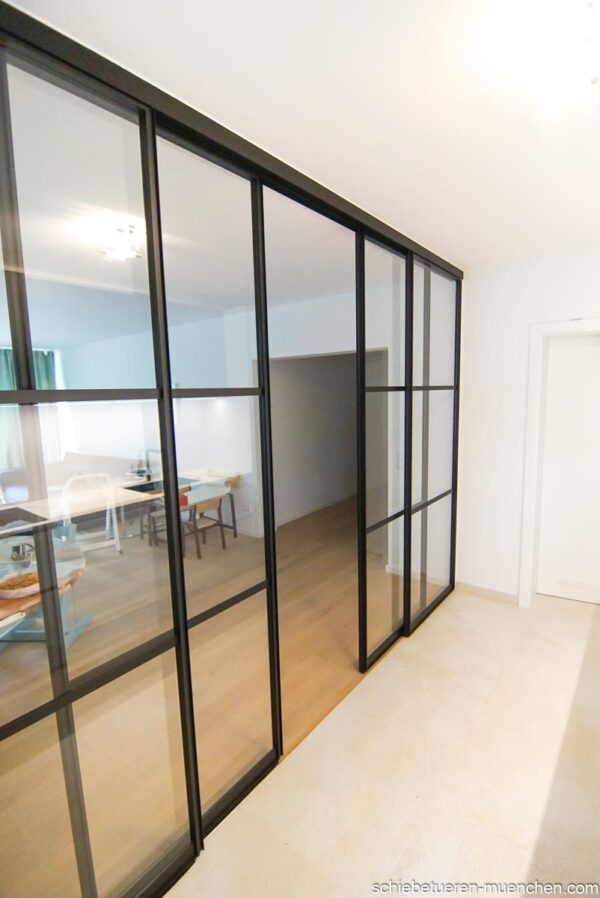 Raumteiler Loft-Schiebetüren teilgeöffnet, schwarze Aluminiumprofile und Klarglas zwischen Küche und Wohnen – door360.