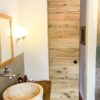 Holz-Schiebetür aus Altholz-Eiche, geschlossen im Badezimmer neben einem Waschtisch mit Natursteinbecken