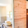 Holz-Schiebetür aus Altholz-Eiche, geschlossen im Badezimmer neben einem Waschtisch mit Natursteinbecken, Deckenmontage.